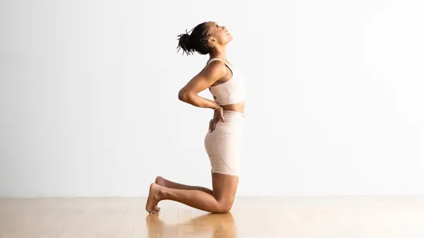 Woman in a Camel Pose modification with hands on sacrum