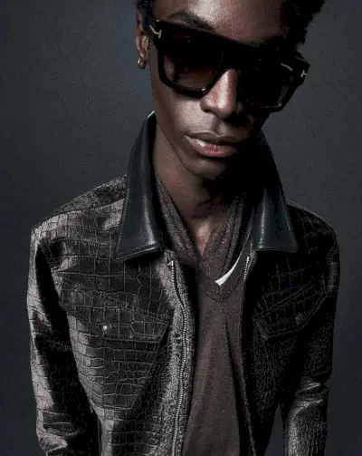 Elegante en negro, Ahmed Richards irradia sofisticación fresca con una chaqueta de cuero con efecto de cocodrilo y gafas de sol clásicas de Tom Ford.