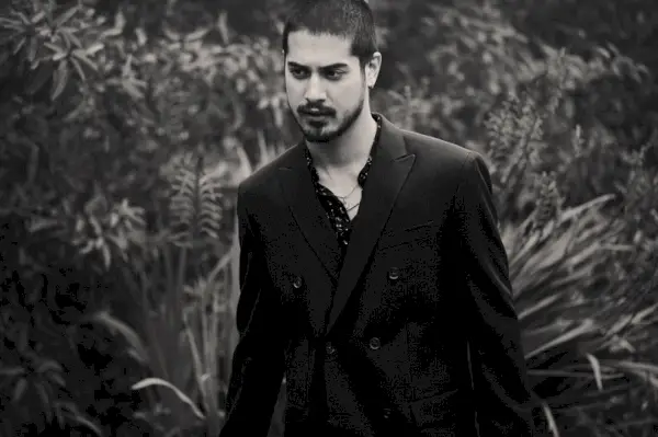 Avan Jogia nosi srajco H&M z suknjičem z dvojnim zapenjanjem Calvin Klein in lastnimi ogrlicami.