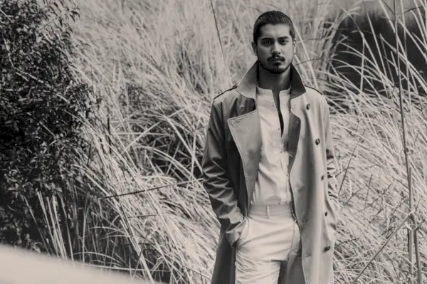 Igralec Avan Jogia obleče trenč H&M s srajco SCYLT in hlačami COS.