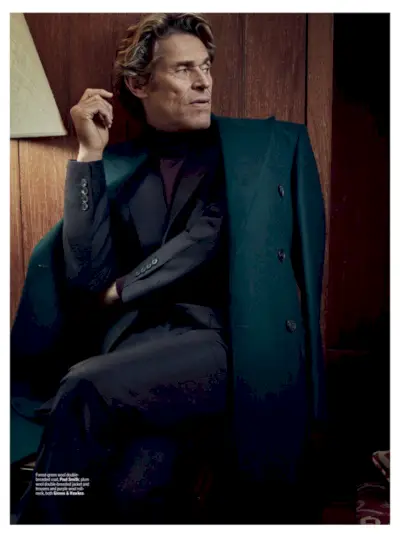 Vision épurée, Willem Dafoe porte un manteau croisé Paul Smith avec un pull et un costume Gieves & Hawkes.