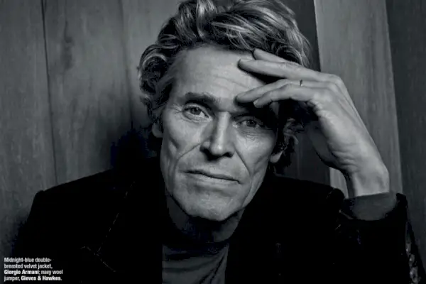 Capturé en noir et blanc, Willem Dafoe porte une veste en velours Giorgio Armani avec un pull Gieves & Hawkes.