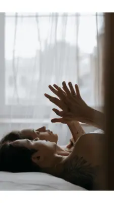 Couple lying in bed pressing their palms against each other while having a quiet conversation
