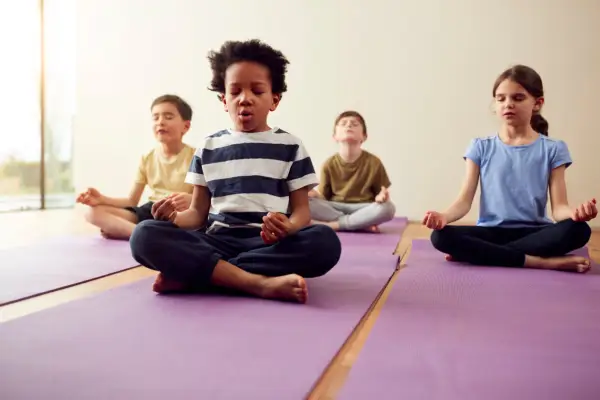 Children practice meditation on purple yoga mats