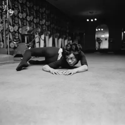 Actor and singer Eartha Kitt in dark leotard and tights practices a complicated twist