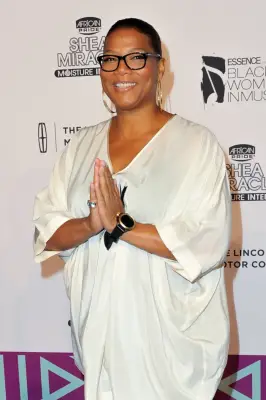 Actor/rapper Queen Latifah in a white top and dark pants holds her hands in a prayer position