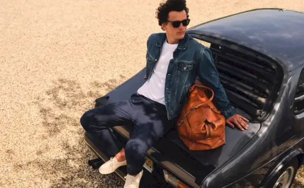 Con un estilo informal, Simon Nessman luce una chaqueta de mezclilla J.Crew con una camiseta relajada de algodón de primera calidad y un pantalón Tech Dock.