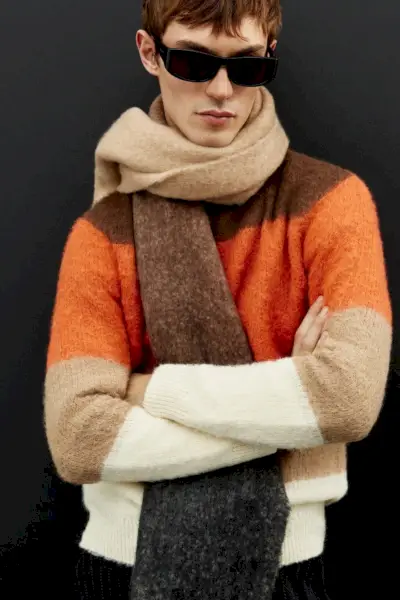 キット・バトラーは、印象的なオレンジとアースカラーの大胆な ZARA ニットウェアを、豪華な特大スカーフで引き立てています。