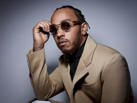 Vêtu de Prada et portant des lunettes de soleil Police, Lewis Hamilton joue dans une séance photo style Corriere della Sera.