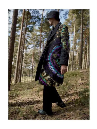 Finnlay Davis, kas izkāpj ar kaklasaites apdruku, modelē obligātu liela izmēra stepētu mēteli no Dries Van Noten.