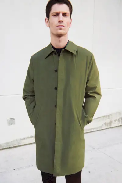 Spredaj in na sredini Justin Eric Martin nosi avto plašč kaki barve.