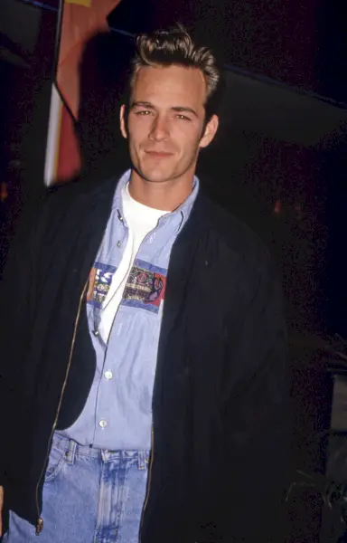 Luke Perry poartă o jachetă bomber cu blugi din denim în această imagine, circa 1991.