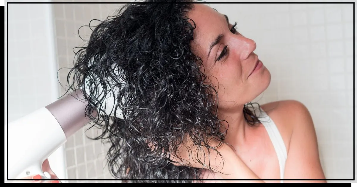 Mujer peinándose el pelo rizado' title=