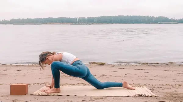 Woman in a low lunge on her yoga mat at the beach during the full Moon in Pisces