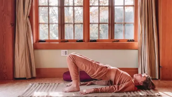 Woman lying on her back practicing Yin Yoga with her hips lifted and her feet pressing into the ground