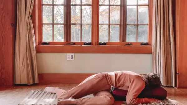 Woman practicing Yin Yoga with her knees bent and her chest twisted to stretch her lower back