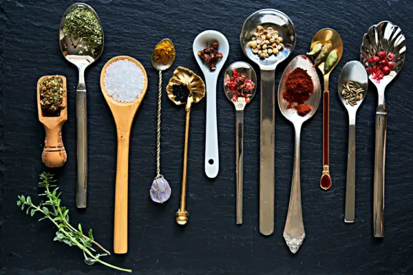 Spoons with Ayurvedic herbs and spices on a dark blue background
