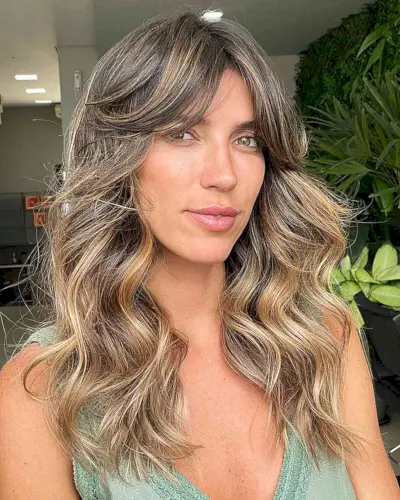 Thick Long Curtain Bangs on Medium-Length Wavy Hair with Blonde Balayage