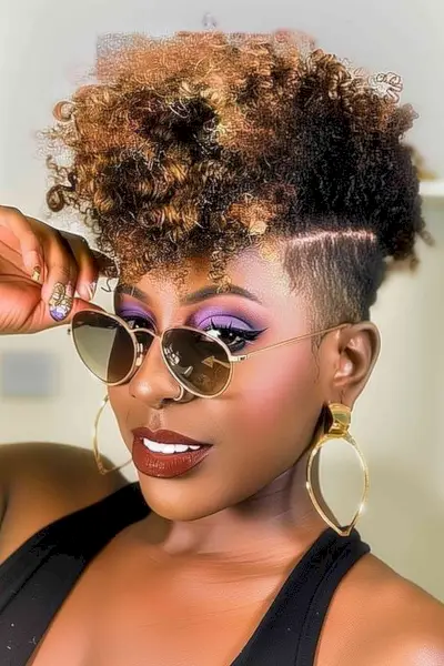 Curly frohawk on 4c hair with honey blonde highlights and tapered sides