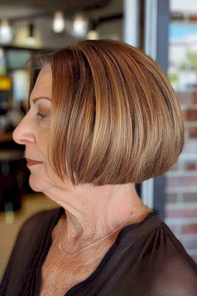 Classic bob with caramel highlights for women over 70, featuring a sleek, straight cut and face-framing layers.