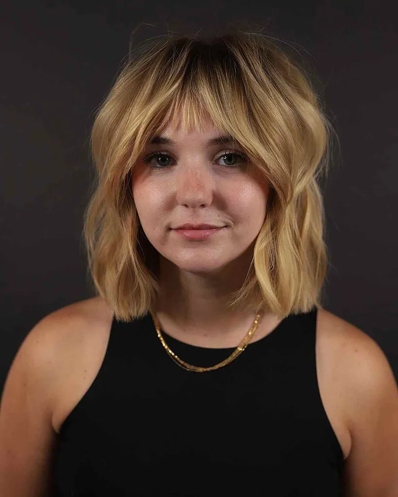 고르지 못한 짧은 프린지가 있는 어깨 길이의 금발 로브' title=