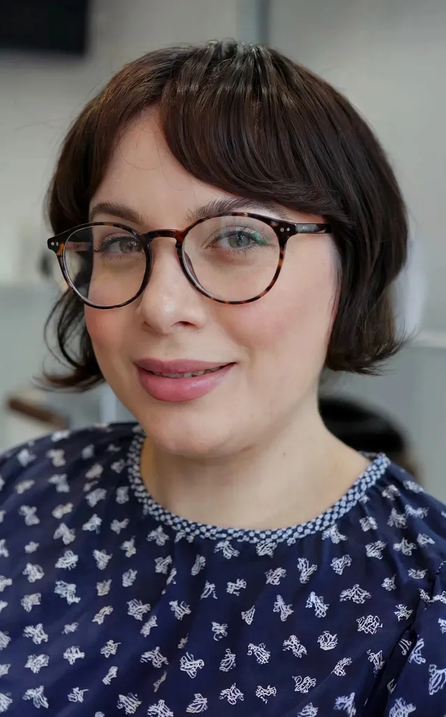 Bob e frangia con parte centrale all'altezza della mascella per forme di viso rotonde con occhiali' title=