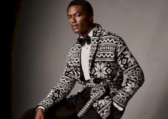 Hamid Onifade poartă un pulover cardigan cu curea tricotat manual de Ralph Lauren Purple Label.