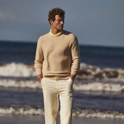 Scendendo in spiaggia, Bas Tijhof indossa un maglione girocollo in cashmere Johnstons of Elgin.