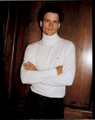 Selvsikker og sammensatt, har Simon Nessman på seg en klassisk hvit turtleneck, som legemliggjør den rene estetikken til Tommy Hilfiger