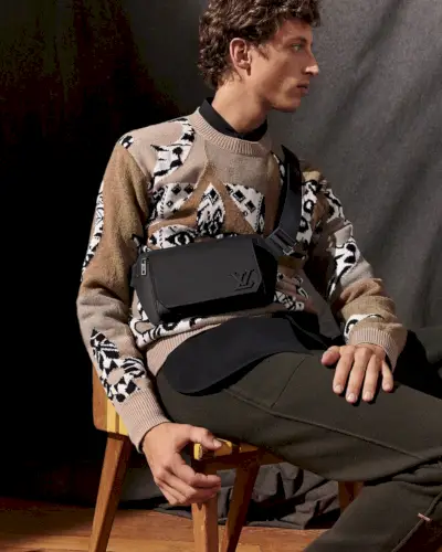 사진을 찍기 위해 앉아 있는 Alexis Maçon-Dauxerre는 Louis Vuitton의 가죽 슬링백을 착용합니다.