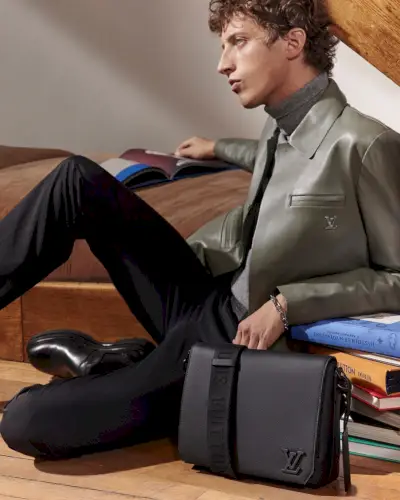 모델 Alexis Maçon-Dauxerre가 루이 비통 가죽 메신저 백을 들고 포즈를 취하고 있습니다.