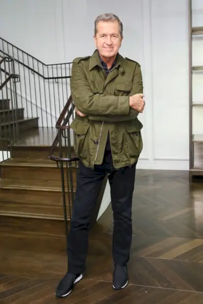 Fotograaf Mario Testino staat vooraan en in het midden in een jasje in militaire stijl.