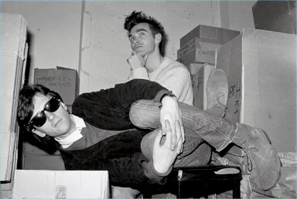 Johnny Marr i Morrissey z The Smiths pozują do zdjęcia. Marr ma na sobie okulary przeciwsłoneczne Ray-Ban Wayfarer.
