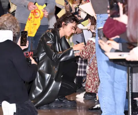 Timothée Chalamet porta un tocco di moda all'aeroporto, salutando i fan con un elegante cappotto in lattice Avellano.