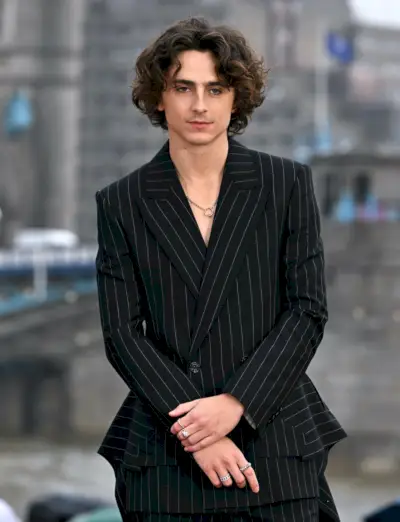 Timothée Chalamet appare disinvoltamente chic in un abito gessato di Alexander McQueen con un caratteristico strascico corto al photocall londinese di Wonka.