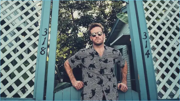 Schauspieler Armie Hammer trägt ein Hemd mit Kragen von Saint Laurent, eine Hose von AMI und eine Sonnenbrille von Oliver Peoples.