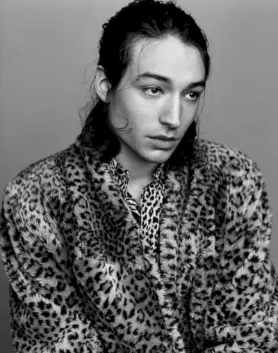 エズラは、ヴィンテージのヒョウ柄のジャケットとサンローランのシャツを着て、白黒のショットでポーズをとっています。