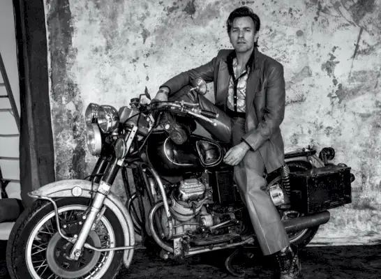 Posando em uma motocicleta, Ewan McGregor veste um terno Gucci para sua sessão de fotos para a capa do VMAN.