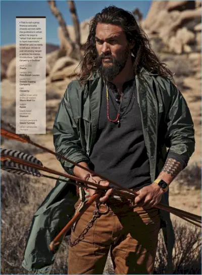 Med hovedrollen i en GQ-fotografering, har Jason Momoa på seg en Prada-frakk med en POLO Ralph Lauren-henley, Duluth Trading Company-bukser og et Eleventy-belte.