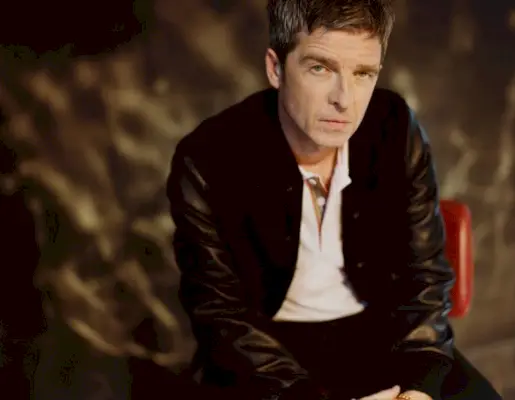 Noel Gallagher trägt eine „Golden Bear“-Bomberjacke aus einer Wollmischung und Leder mit einem mit dem Burberry-Logo bestickten, kontrastierenden Baumwoll-Piqué-Poloshirt und erscheint in „Mr. Porter“.