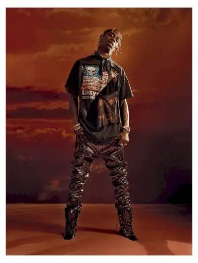 Vepředu a uprostřed má Travis Scott sportovní kalhoty Louis Vuitton, šátek Alexander Wang a vintage tričko.