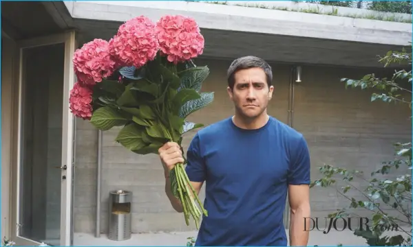Tenant un bouquet de fleurs, Jake Gyllenhaal arbore un t-shirt Sunspel avec un pantalon Hermès.