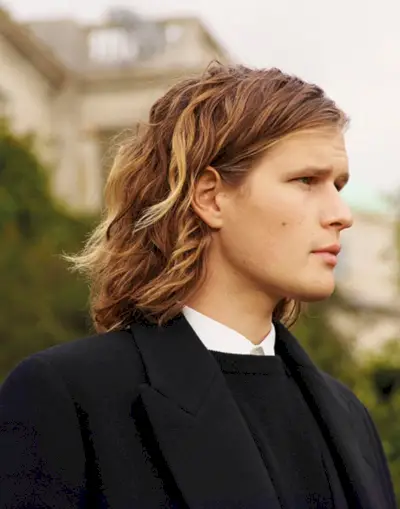 Als Seitenprofil trägt Lord March einen zweireihigen Kaschmirmantel, ein Hemd und einen schmal geschnittenen Kaschmirpullover von The Row.