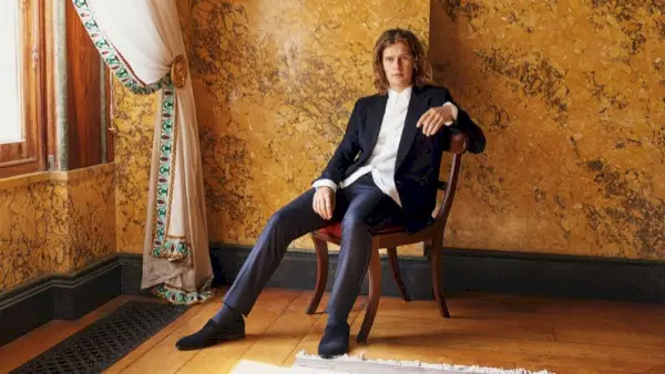 Lord March sitzt für ein Porträt und trägt ein Hemd und einen Smoking von The Row.