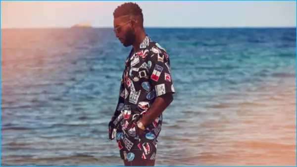 Tinie Tempah trägt ein bedrucktes Hemd mit Camp-Kragen und Badeshorts von Maison Kitsuné.