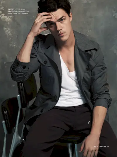 Finn Wittrock na zdjęciu w trenczu Brioni, podkoszulku Dsquared2 i spodniach Ermenegildo Zegna.