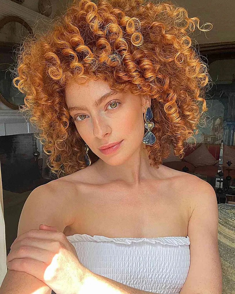 אישה בגזרת Cadō באורך הצוואר המציגה תלתלים קופצניים ושכבות אסטרטגיות לסגנון נפח שובב.' title=