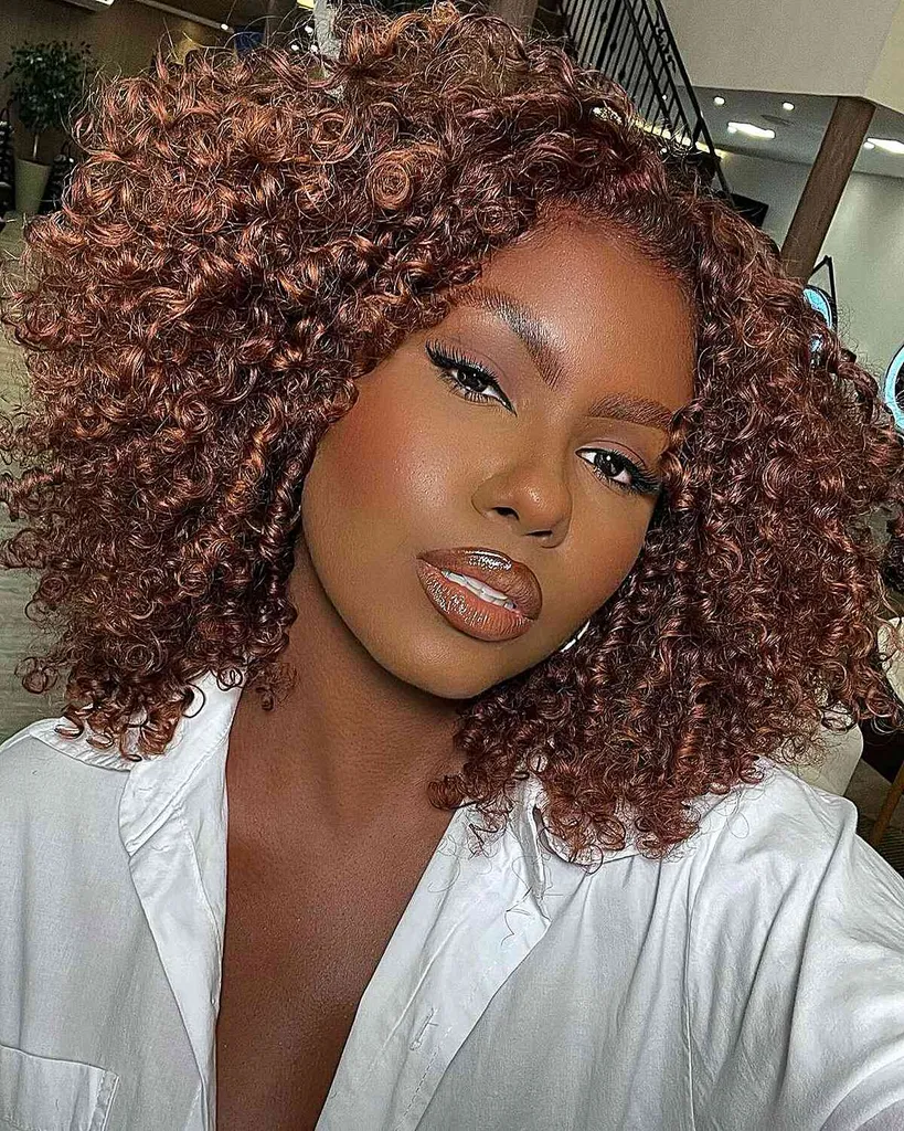 תלתלים טבעיים בגזרת Cadō עם חלק באמצע עם צבע ערמוני חם המציע נפח וצלצולים מוגדרים למראה מאוזן.' title=