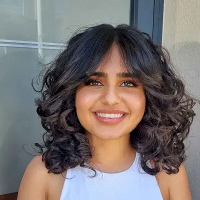 Shoulder-Length Wavy Curls with curtain bangs for a Round Face