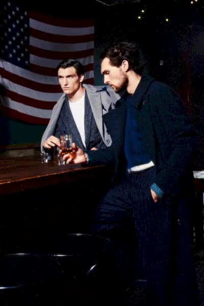 Zľava doprava: Daniel má na sebe kabát Salvatore Ferragamo, tričko Calvin Klein a oblek Pal Zileri. Samuel má na sebe sveter Belstaff, pásikové nohavice agnes b a kabát Pal Zileri.